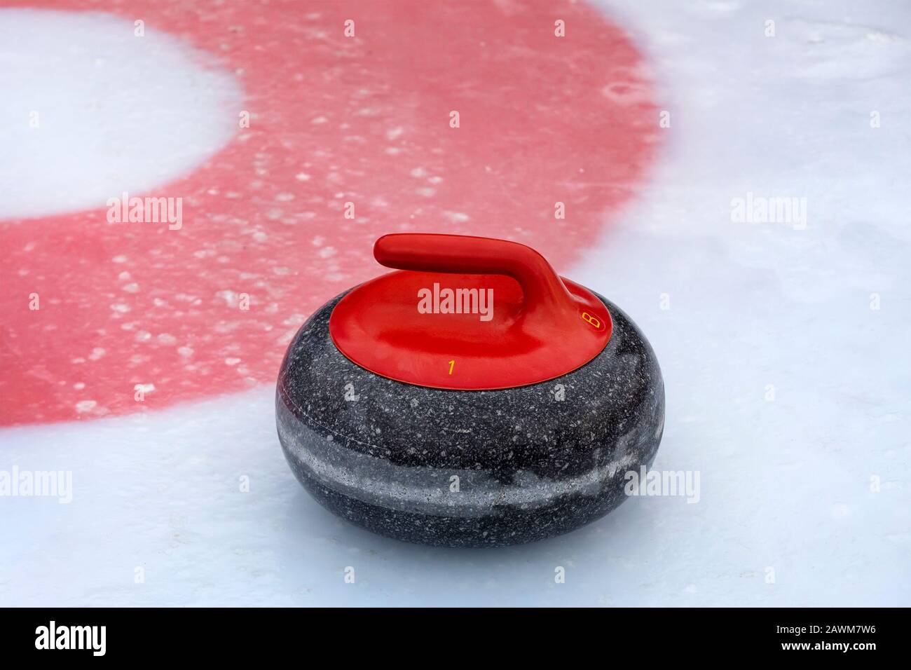 Una pietra curling rossa sul ghiaccio vicino al centro di una casa Foto Stock