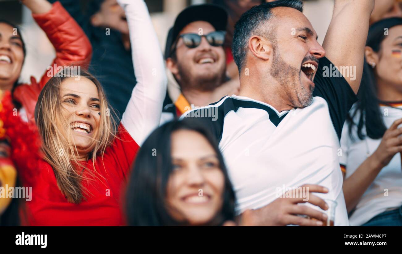 Gruppo di tifosi di calcio che guardano un evento sportivo e rallegrano. Folla di appassionati di sport che si rallegrano nello stadio. Foto Stock