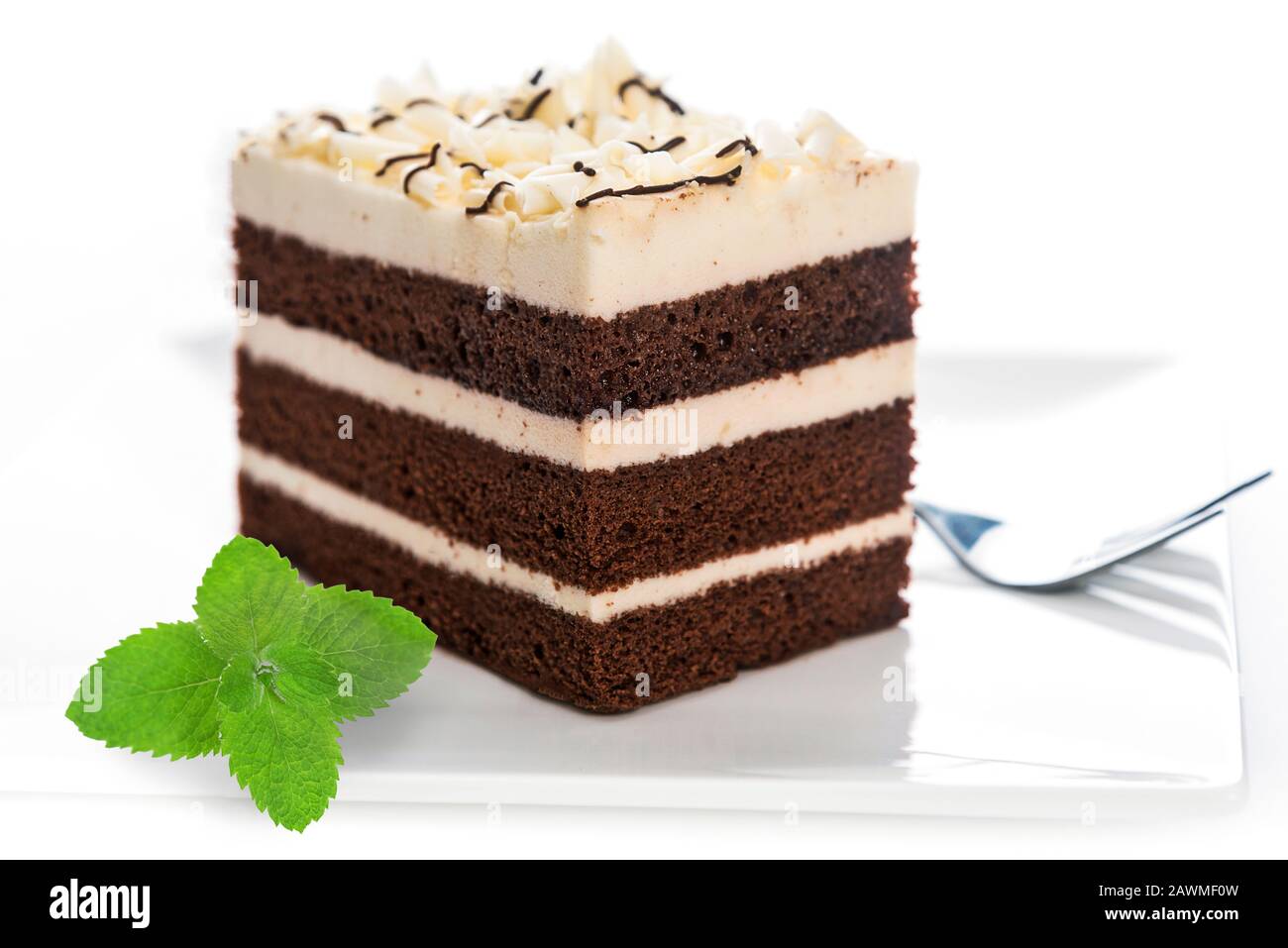 Delizioso pan di Spagna di cacao multistrato fatto in casa con massa di zucchero su un piatto con una forchetta e foglie di menta in primo piano Foto Stock