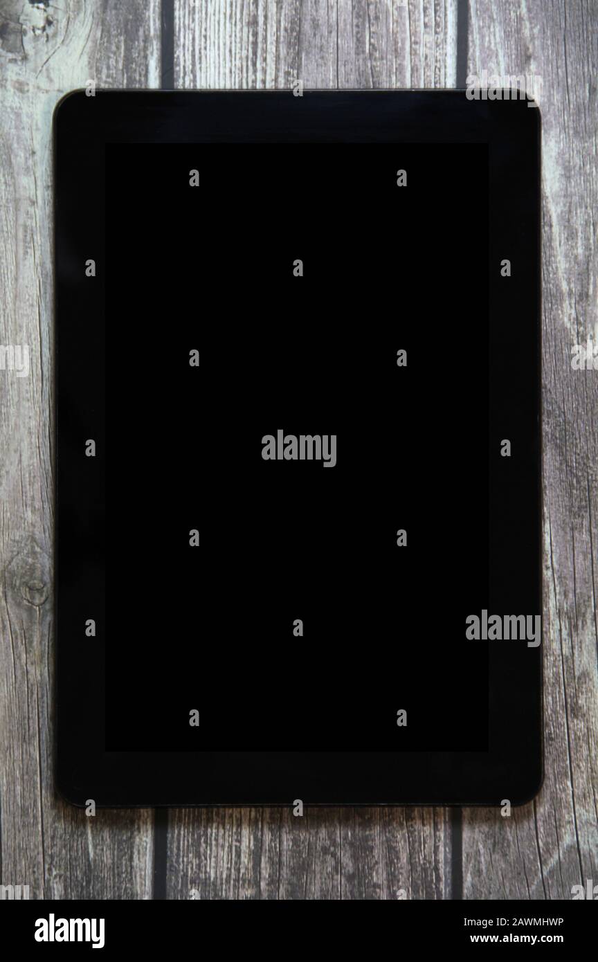 Un tablet con uno schermo nero vuoto si trova su uno sfondo di tavole di legno. Posizionare il testo per il progetto. Foto Stock