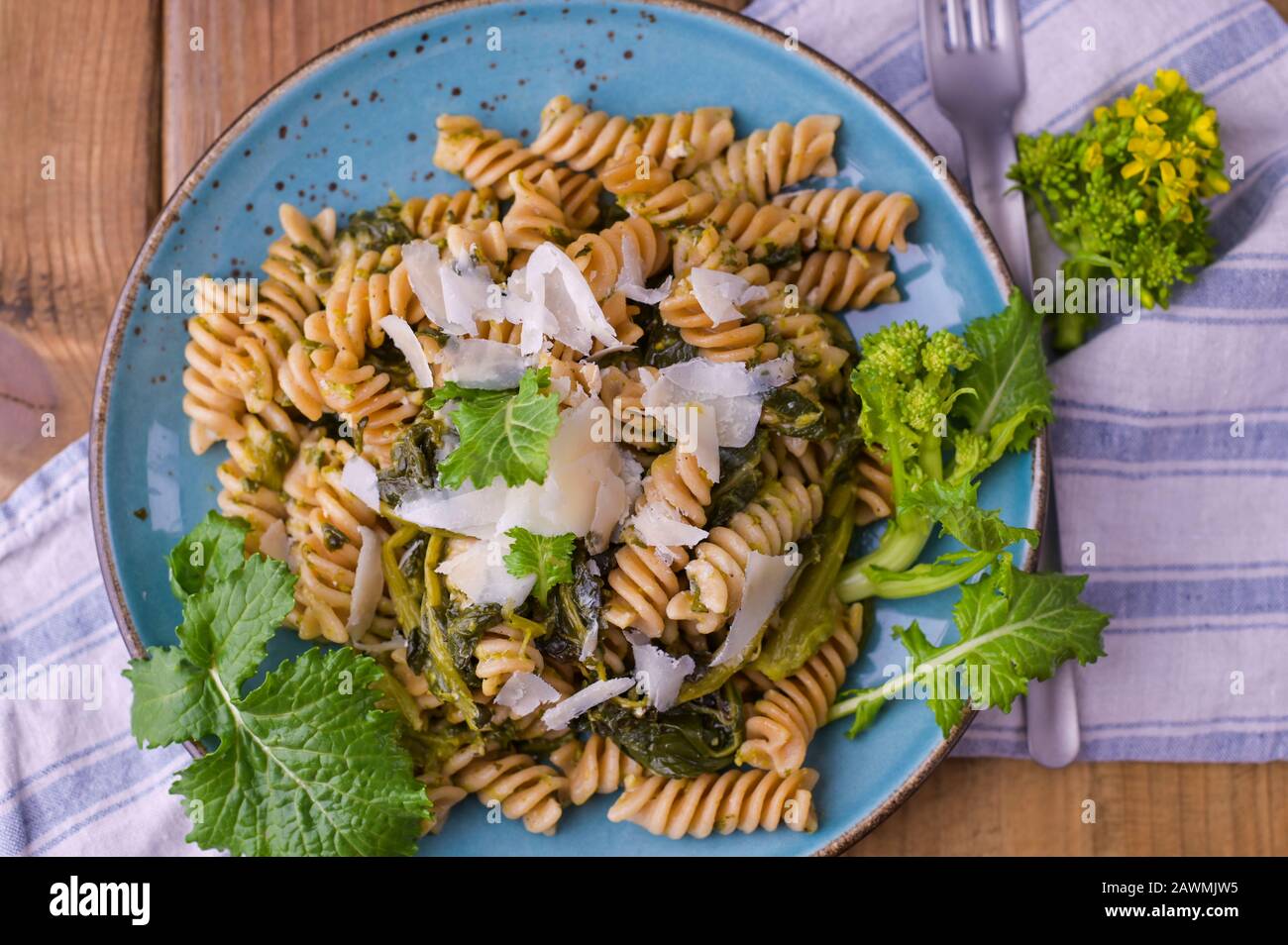 Cime di rapa in un piatto con parmigiano su un tavolo di legno. Cucina tradizionale del sud d'Italia, dalla Puglia. Foto in stile rustico. Foto Stock