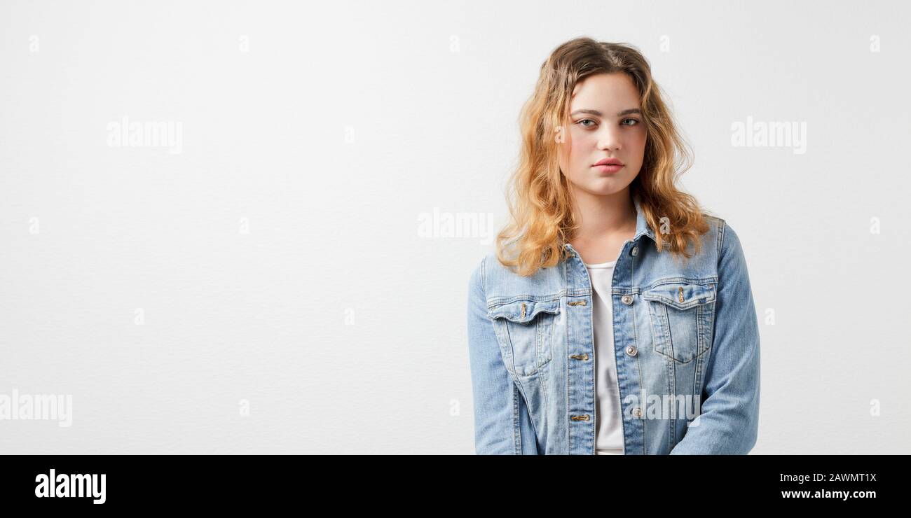 Ritratto a mezza lunghezza di una giovane ragazza europea in una giacca in denim su sfondo bianco. Foto Stock