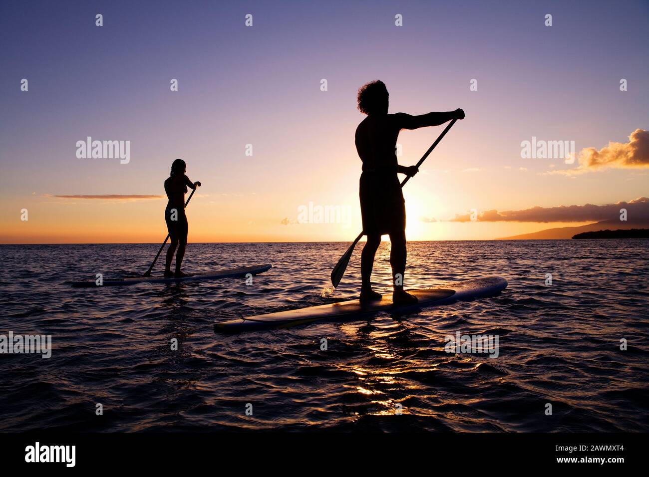 Le palette per coppie sane si alzano in piedi sulle tavole da paddle al tramonto a Olowalu, Maui, Hawaii. Foto Stock