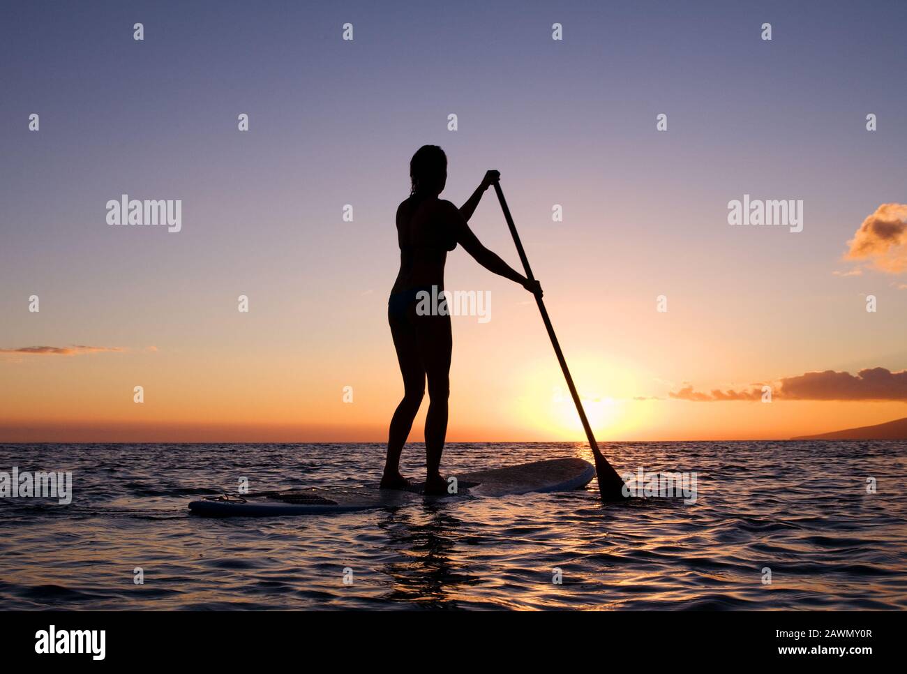 Sano, misura donna pagaia un stand up paddle board al tramonto a Olowalu, Maui, Hawaii Foto Stock