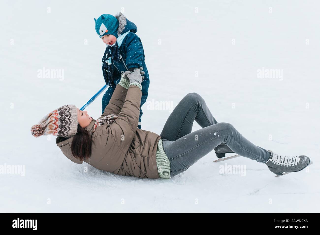 Piccolo ragazzo divertente che impara a pattinare con la madre nel parco. All'aperto. Sport invernali. Foto Stock