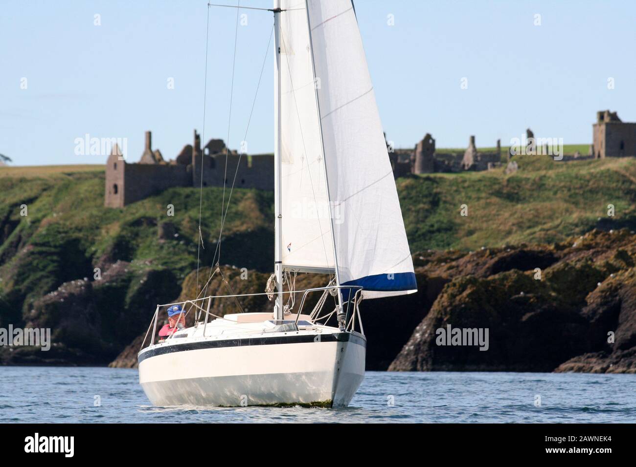 Piccolo yacht a vela al largo del castello di Dunnottar, Stonehaven, Aberdeenshire, Scozia Foto Stock