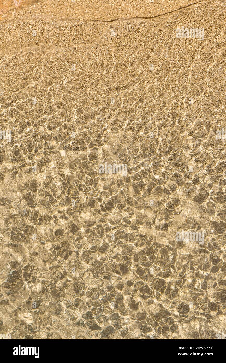 Spiaggia rocciosa e acqua ondulata trasparente vista dall'alto. Immagine a fotogramma intero naturale astratta. Foto Stock