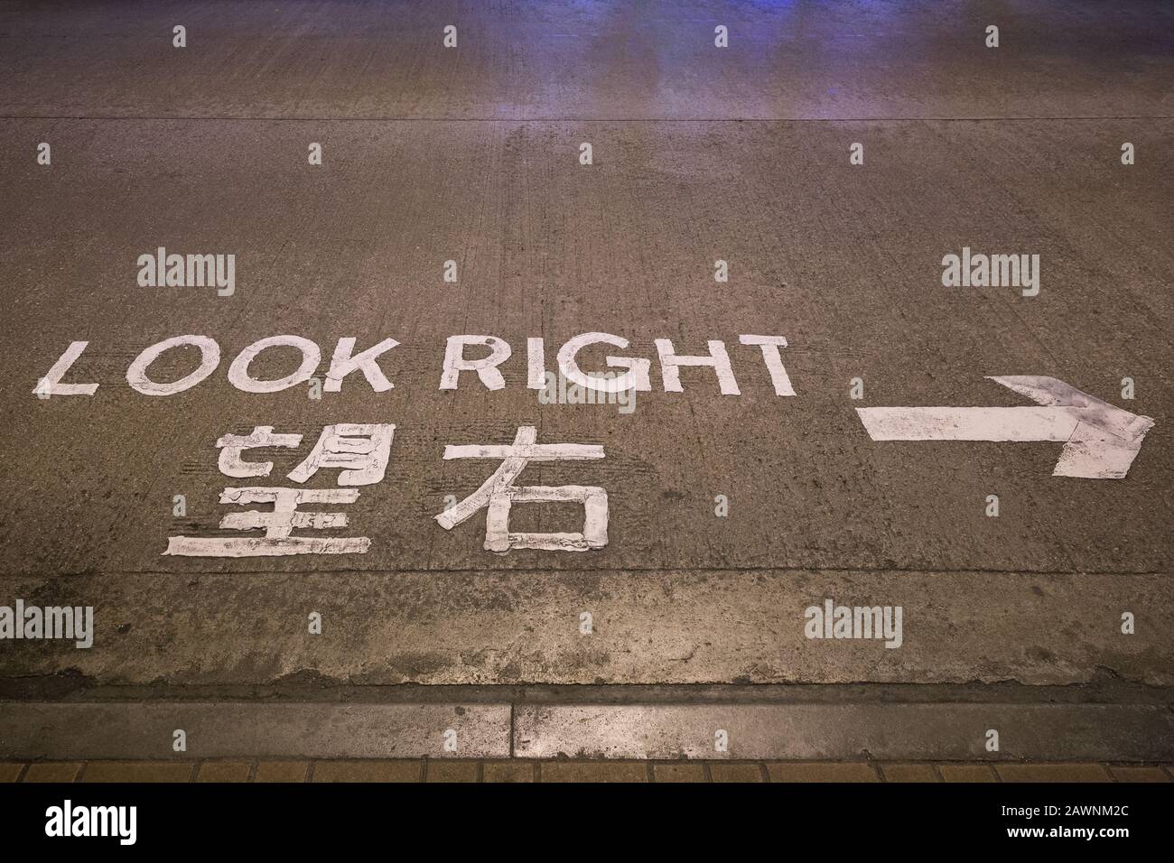 Freccia e 'guardare a destra' attenzione o segno scritto in inglese e cinese su una strada a Hong Kong, Cina. Foto Stock