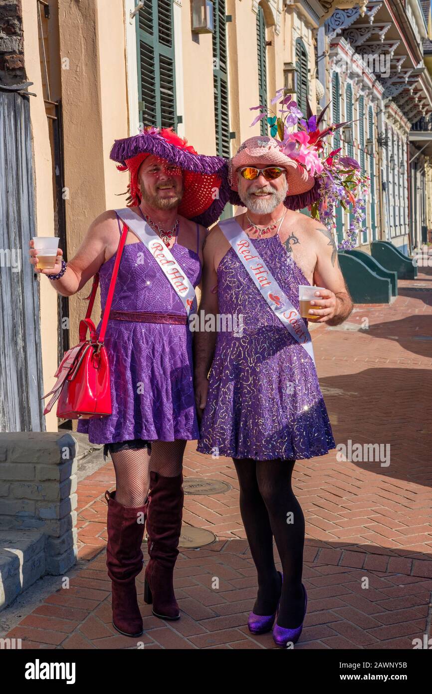 Coppia LGBT, due crossdressers maschi maturi che indossano le ceneri della Red Hat Society, bevendo in una strada al quartiere francese di New Orleans, New Orleans, Louisiana Foto Stock