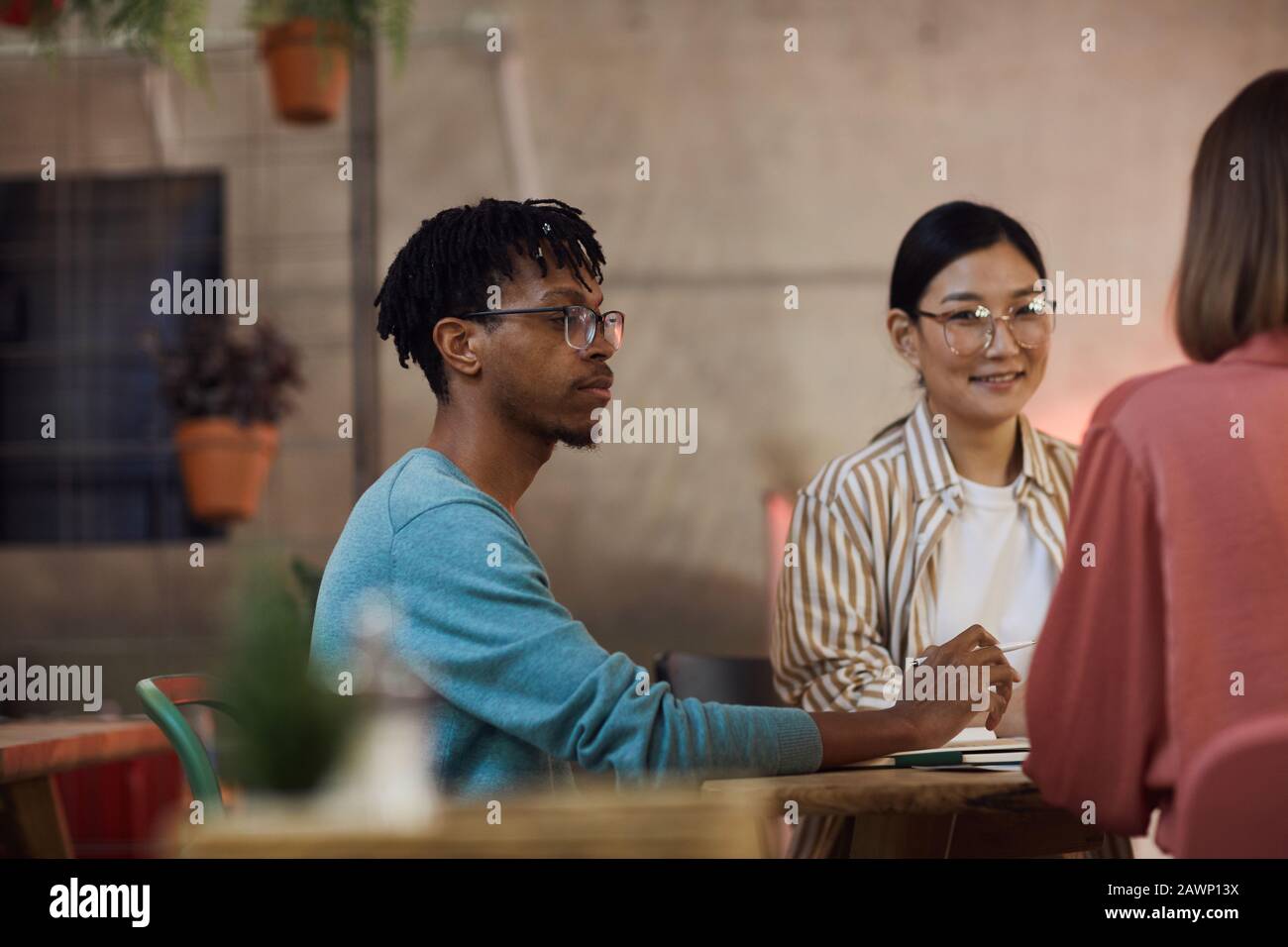 Gruppo multietnico di tre giovani che lavorano insieme al progetto mentre si siedono al tavolo in caffetteria, copia spazio Foto Stock