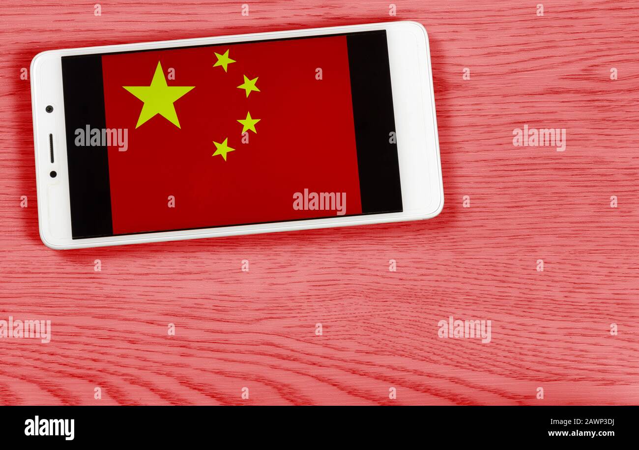 Bandiera della Cina composta posizionando uno smartphone che mostra il suo simbolo su uno sfondo di legno colorato Foto Stock