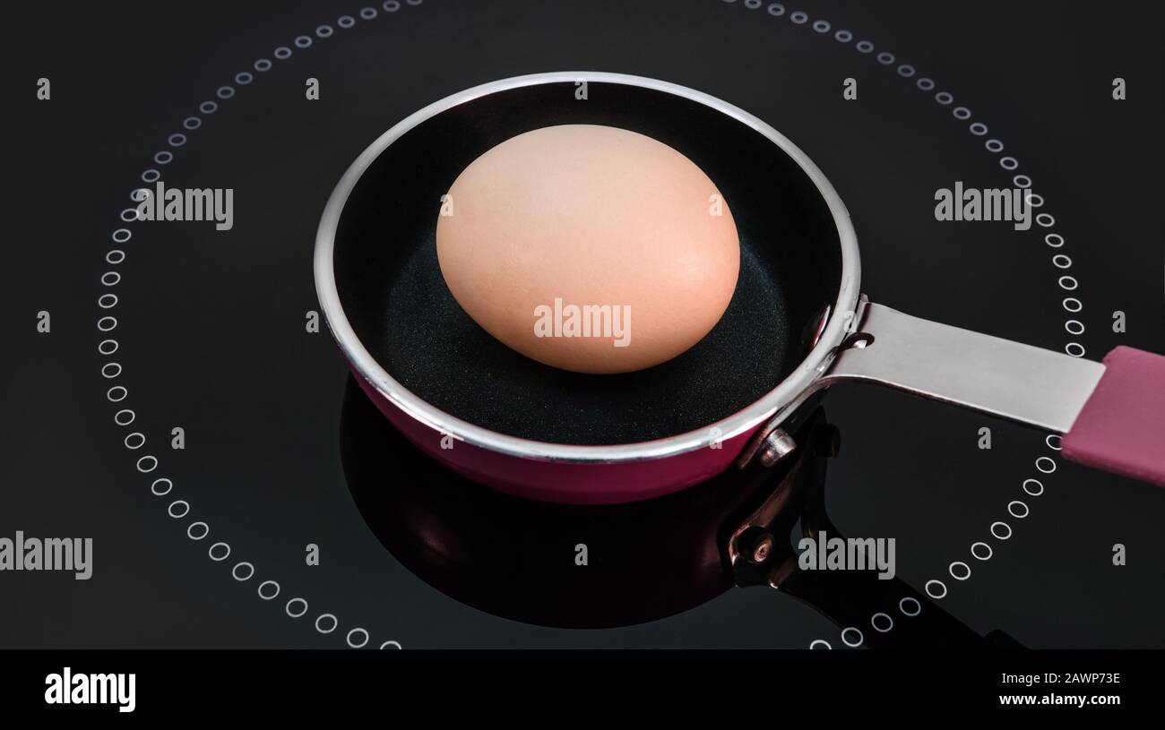 Un uovo in un piccolo tegame, al centro della superficie di cottura. Foto Stock