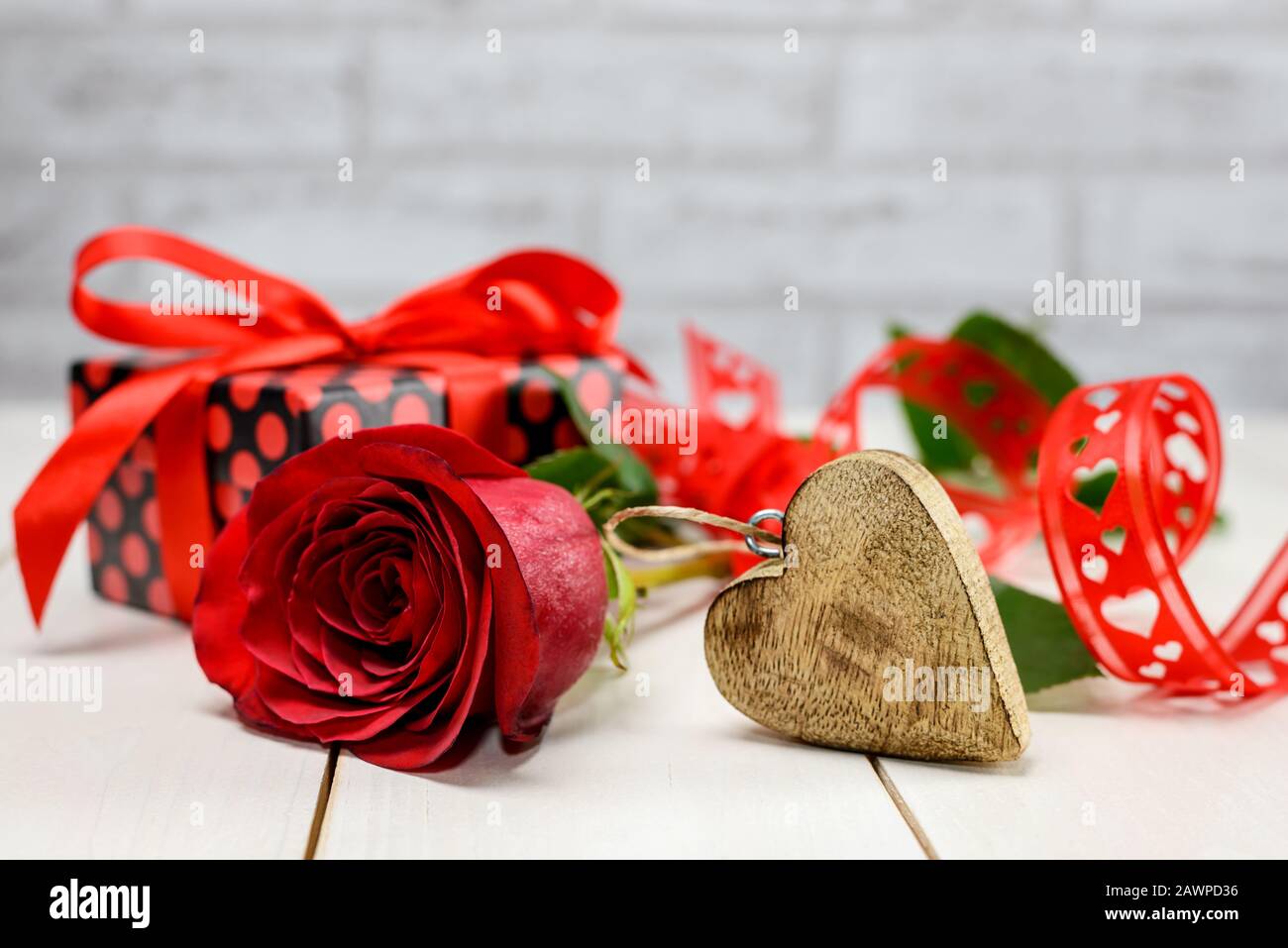 Rosa rossa, cuore in legno, nastro rosso e scatola regalo su tavola in legno bianco con spazio per il testo. Concetto di carta per San Valentino e per il giorno della donna. Foto Stock