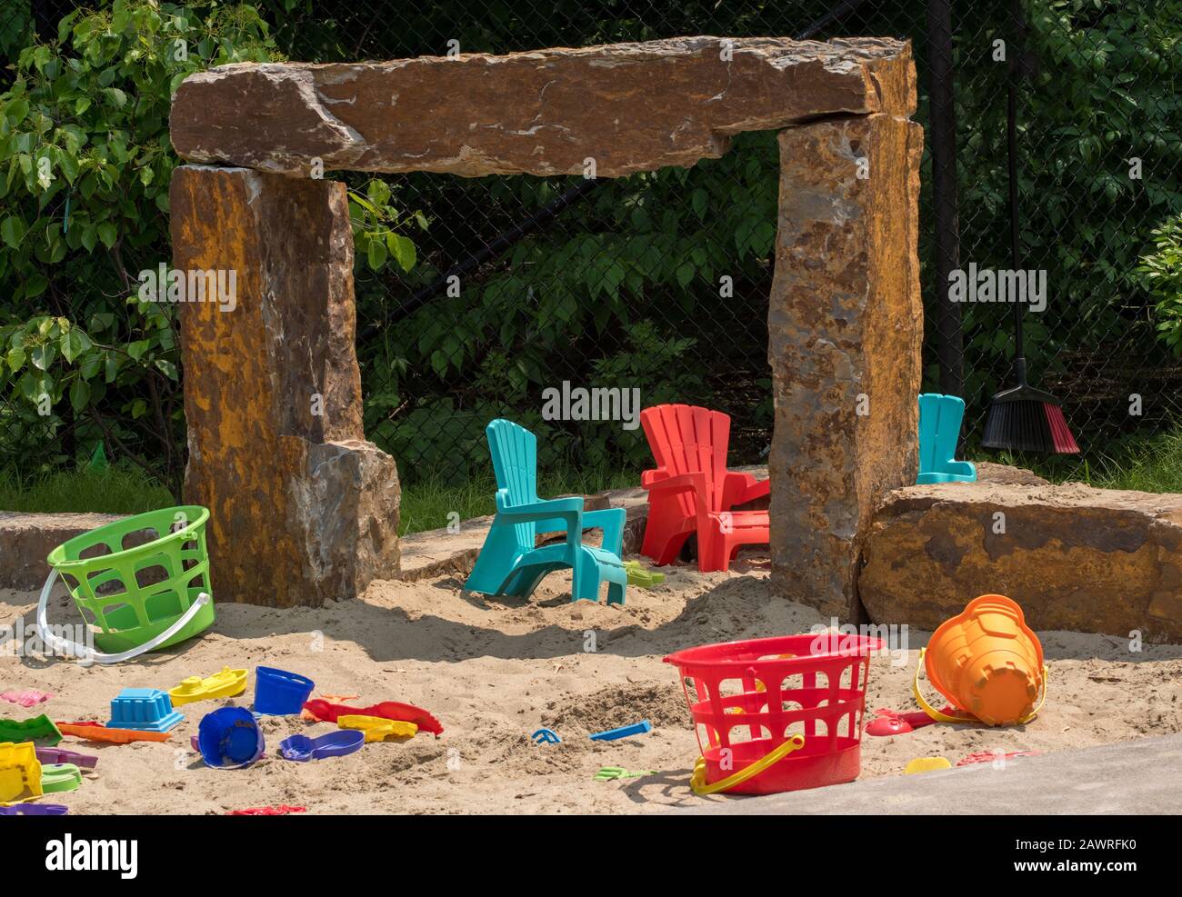 Un grande sandbox in un parco è pieno di giocattoli colorati di sabbia e piccole sedie per bambini Foto Stock