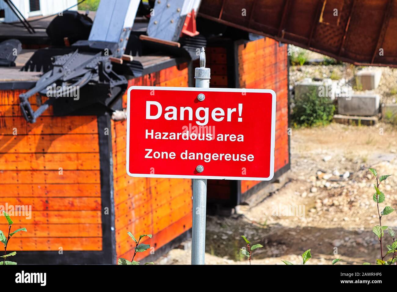 Un cartello rosso di pericolo per le aree pericolose in inglese e francese Foto Stock