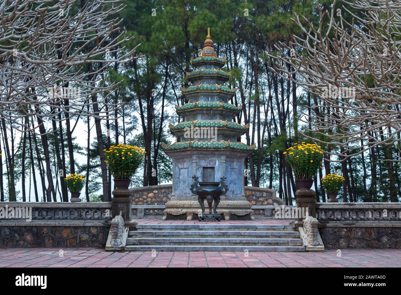 Torre Buddista circondata da Rami di albero Sterile all'interno della Pagoda Thien Mu o Pagoda della Signora Celeste, un tempio storico a Hue, Vietnam Foto Stock