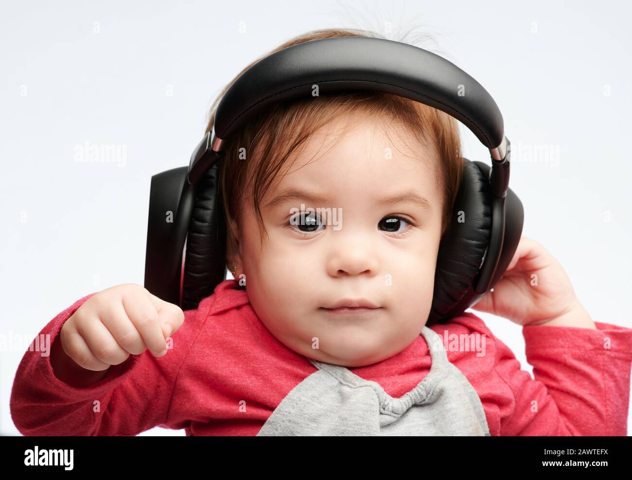Baby girl con cuffie primo piano ritratto isolato su sfondo bianco studio Foto Stock