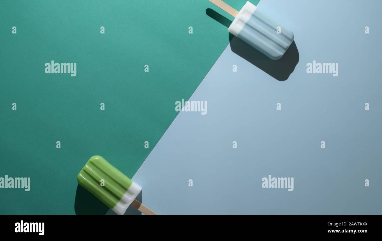 Foto aerea di lime e lampone blu sapore poppicles e copia spazio, estate concetto minimo su piatto laici verde e blu sfondo Foto Stock