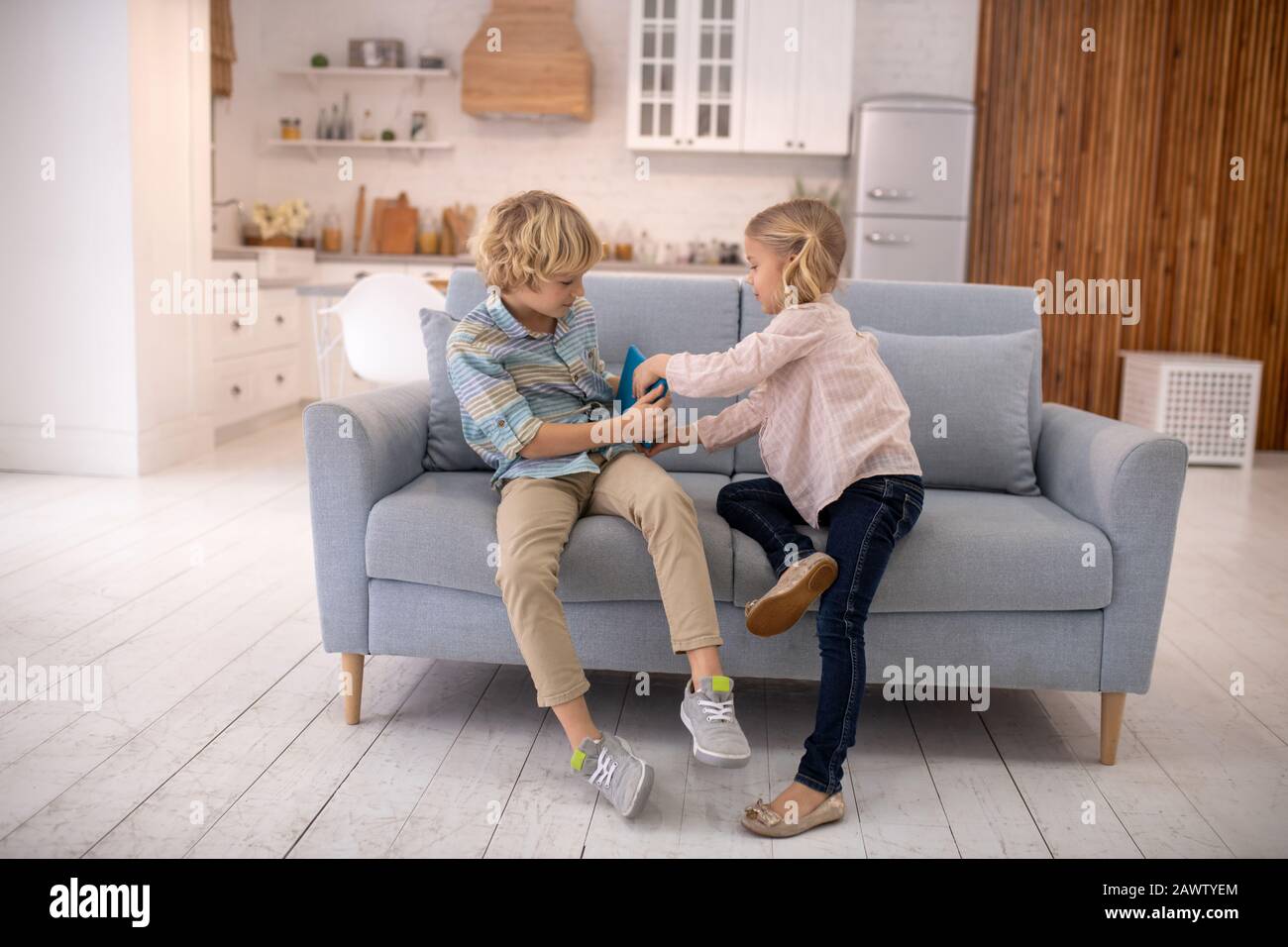 I bambini combattono, prendendo un tablet l'uno dall'altro Foto Stock