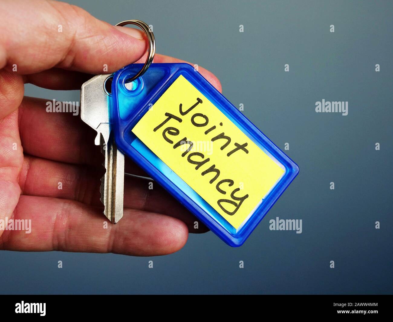 La mano tiene la chiave con l'iscrizione del tenancy del giunto. Foto Stock