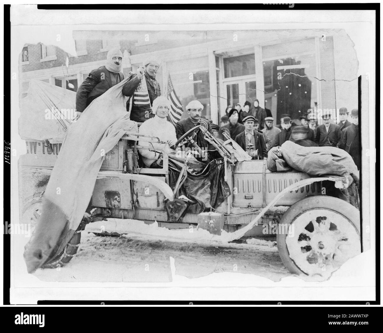 Quattro uomini in automobile, con bandierine americane su neve street, sul New York a San Francisco gamba del 1908 New York a Parigi gara automobilistica Foto Stock