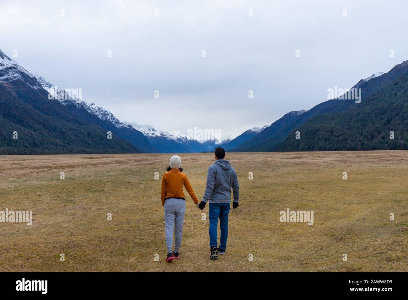 Giovane coppia asiatica che tiene le mani che camminano nel Parco Nazionale Fiordland della valle Eglinton della montagna Nuova Zelanda Foto Stock