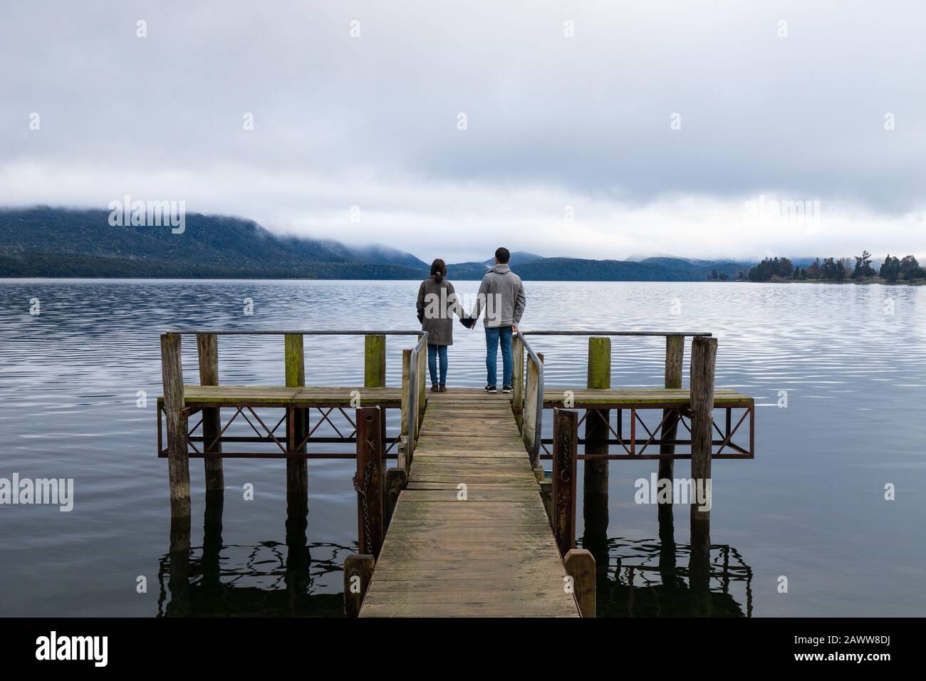 Giovane coppia asiatica che tiene le mani sul ponte Lago te Anau Nuova Zelanda Foto Stock
