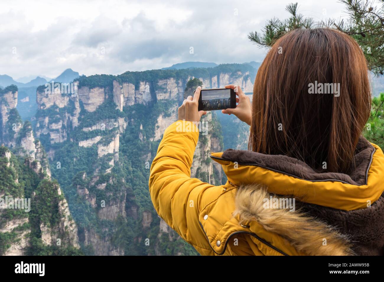 Ragazza turistica asiatica scattare una foto utilizzando uno smartphone al Parco Nazionale della Foresta di Zhangjiajie, sito Patrimonio dell'Umanità dell'UNESCO, Wulingyuan, Hunan, Cina Foto Stock