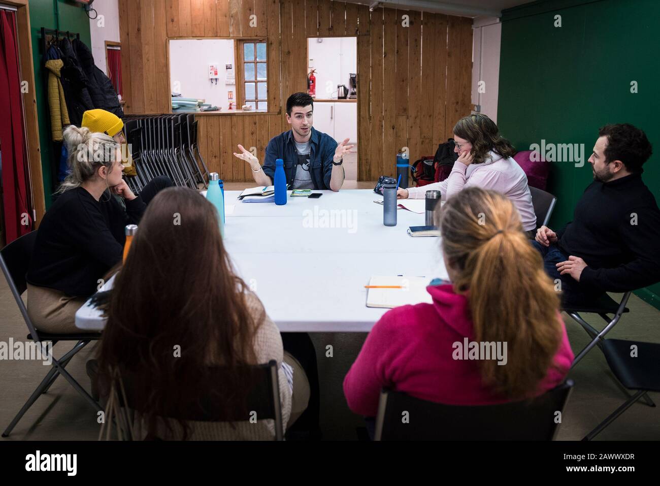 Attori in una sala prove ascoltando un regista che parla della ricerca e dello sviluppo di nuove opere teatrali. Foto Stock