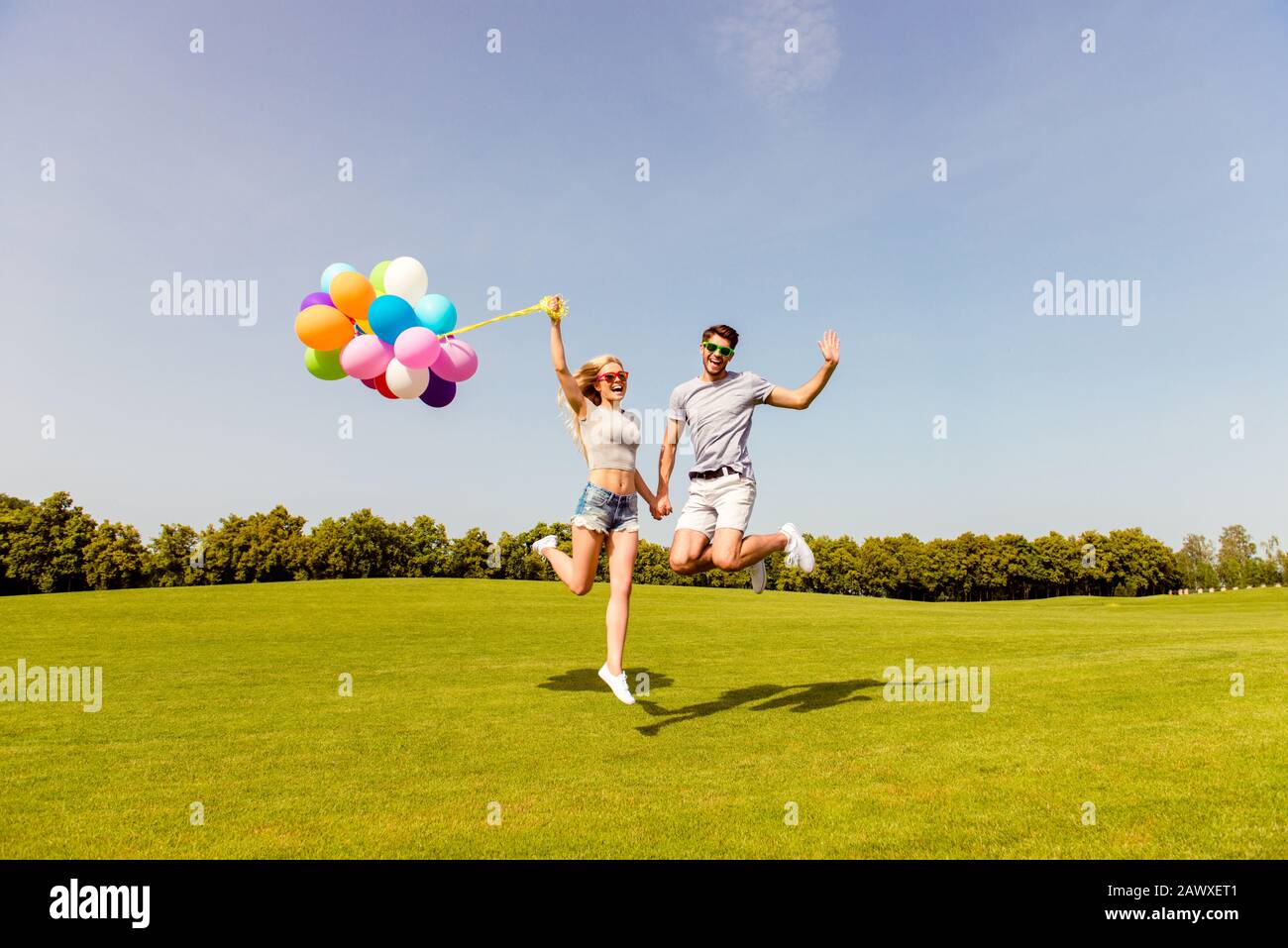 Coppia felice nell'amore che ha divertimento e saltando con i palloncini Foto Stock