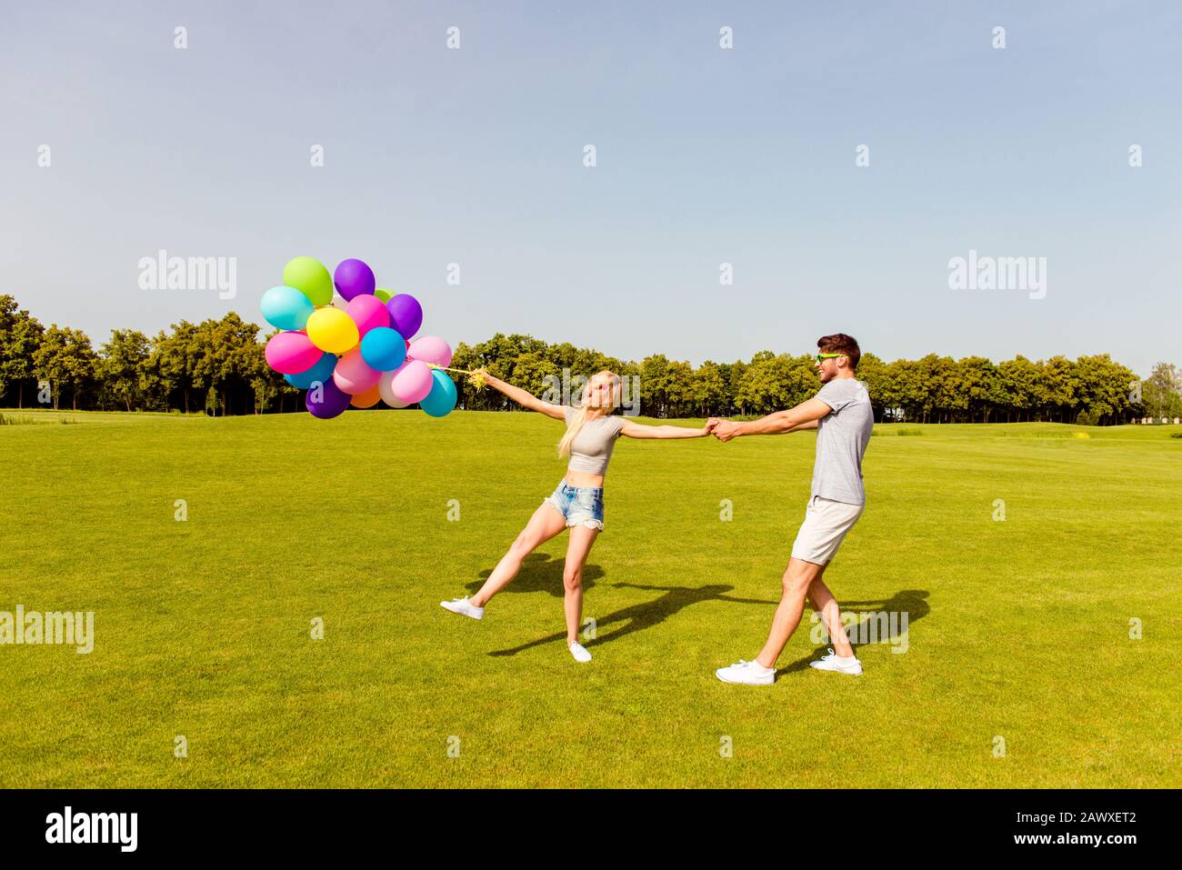 Giovane uomo felice che porta la sua ragazza con palloncini Foto Stock