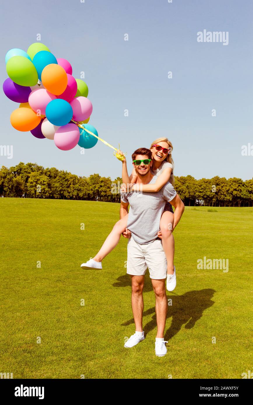 Felice bell'uomo che porta la sua ragazza con palloncini Foto Stock