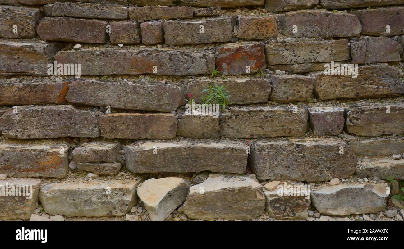muretto abbandonato e rotto muro di roccia, vecchia parete di roccia per lo sfondo Foto Stock