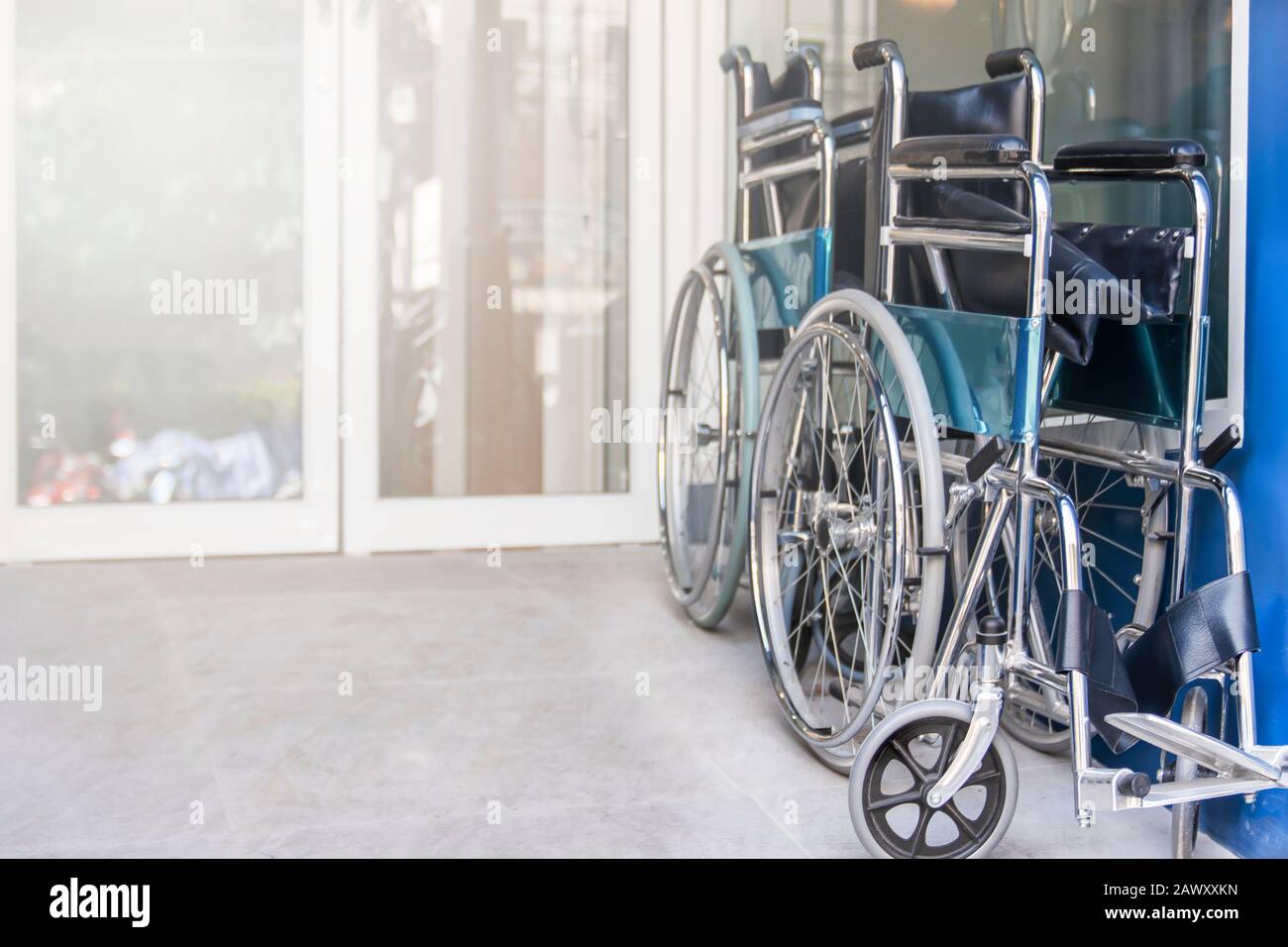 Le sedie a rotelle sono ripiegate e parcheggiate all'entrata dell'ospedale, le apparecchiature mediche per l'uso come mezzo di trasporto da parte di una persona che non è in grado di camminare di conseguenza Foto Stock