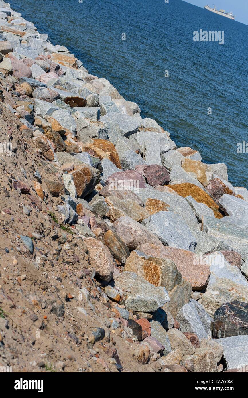 Blocchi di diversi tipi di pietre che rendono il rafforzamento della riva del mare Foto Stock