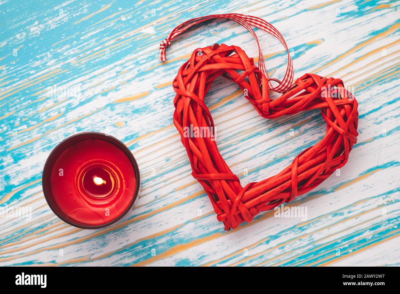 Cuore rosso fatto in casa e candela bruciante su sfondo di legno blu. Romantica carta regalo festiva il giorno delle feste in San Valentino. Simbolo di amore, sfondo romantico Foto Stock