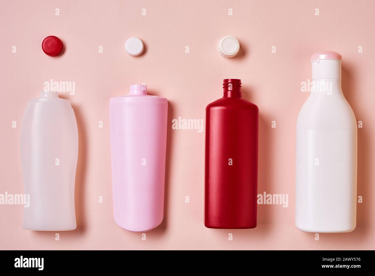 Immagine concettuale orizzontale dall'alto a posa piatta di bottiglie in plastica con top su sfondo rosa pallido Foto Stock