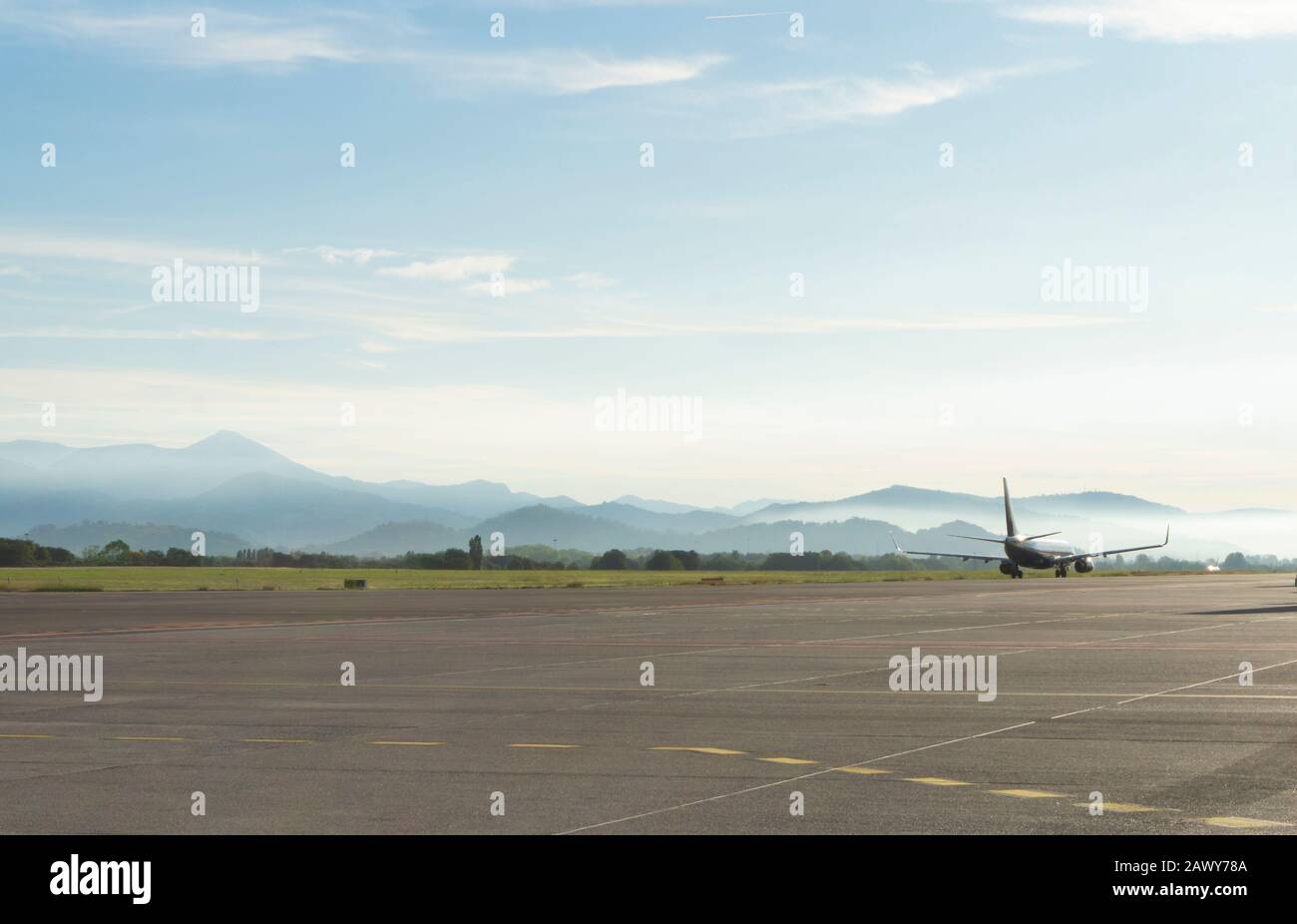 Un aereo passeggeri sull'ampia pista si prepara al decollo la mattina presto all'aeroporto nelle nebbiose montagne di Bergamo Foto Stock