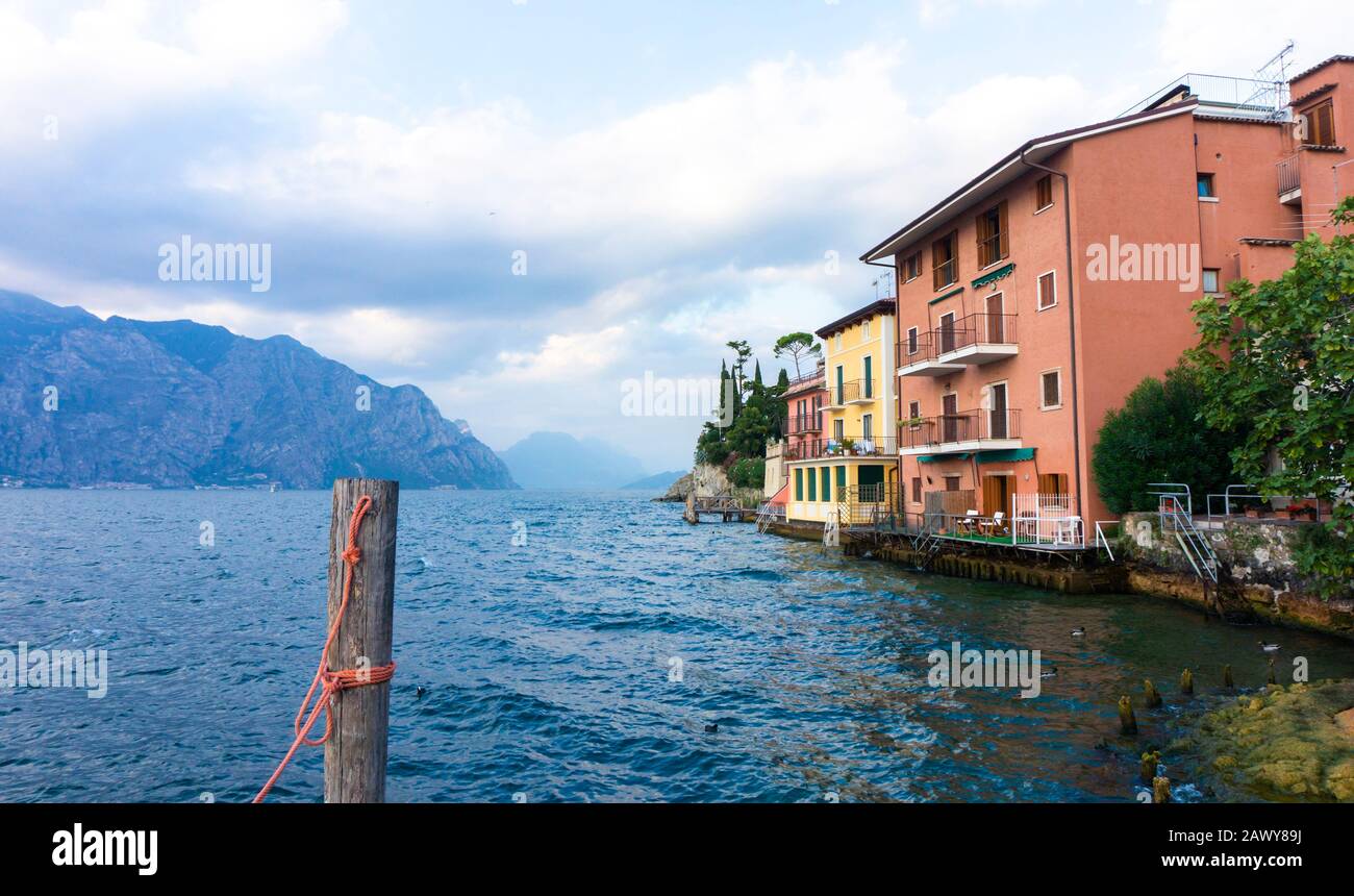 Incantevole vista di una vecchia città europea sopra un lago di montagna. Cartolina con vista dal molo sul argine del villaggio italiano. Foto Stock