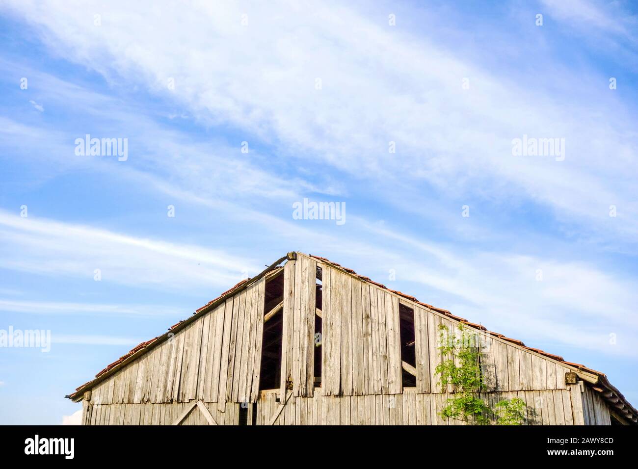 Tetto di un vecchio fienile rotto, cielo blu con nuvole Foto Stock