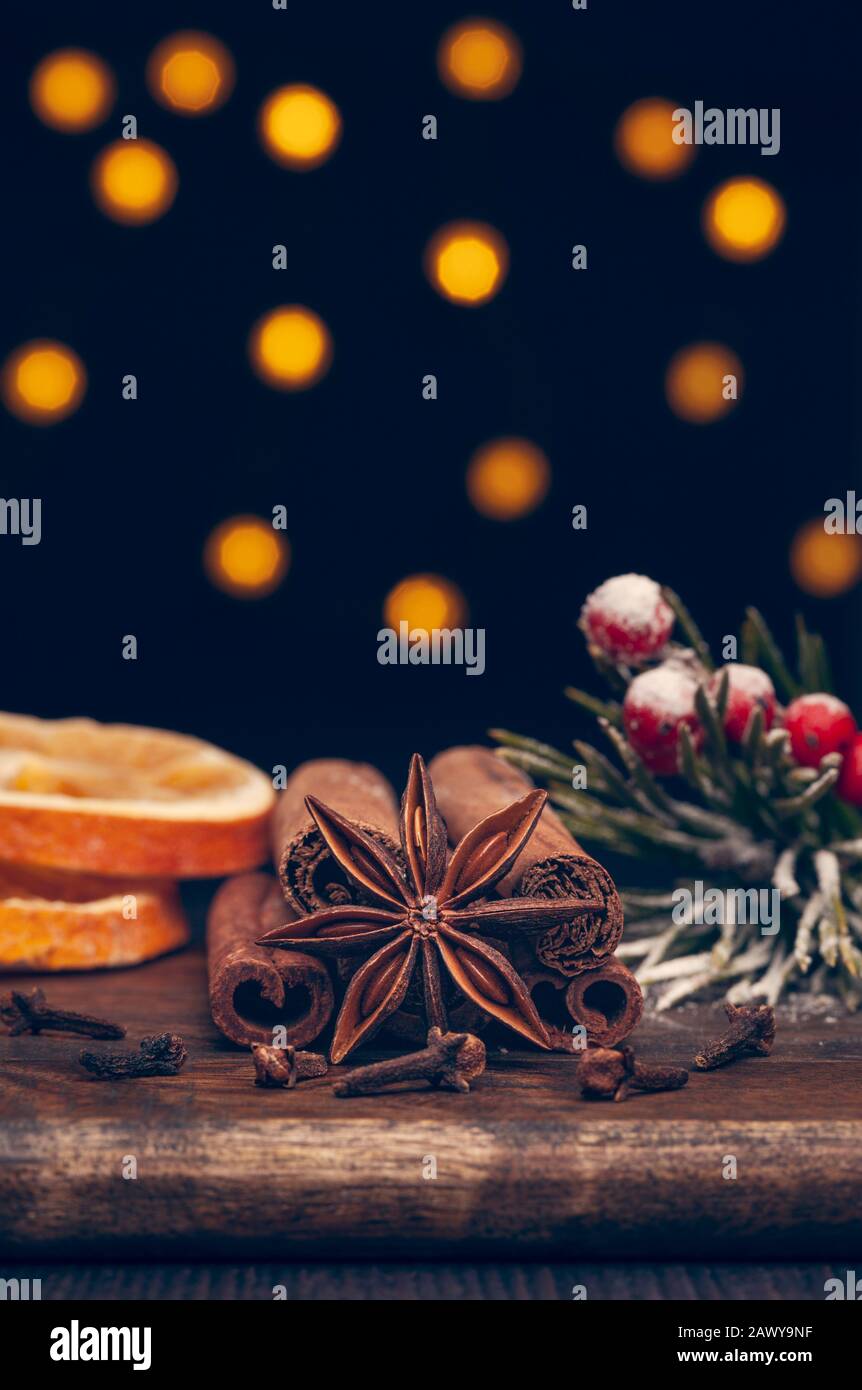 Spezie di Natale su tavola di legno con luci sfocate sullo sfondo Foto Stock