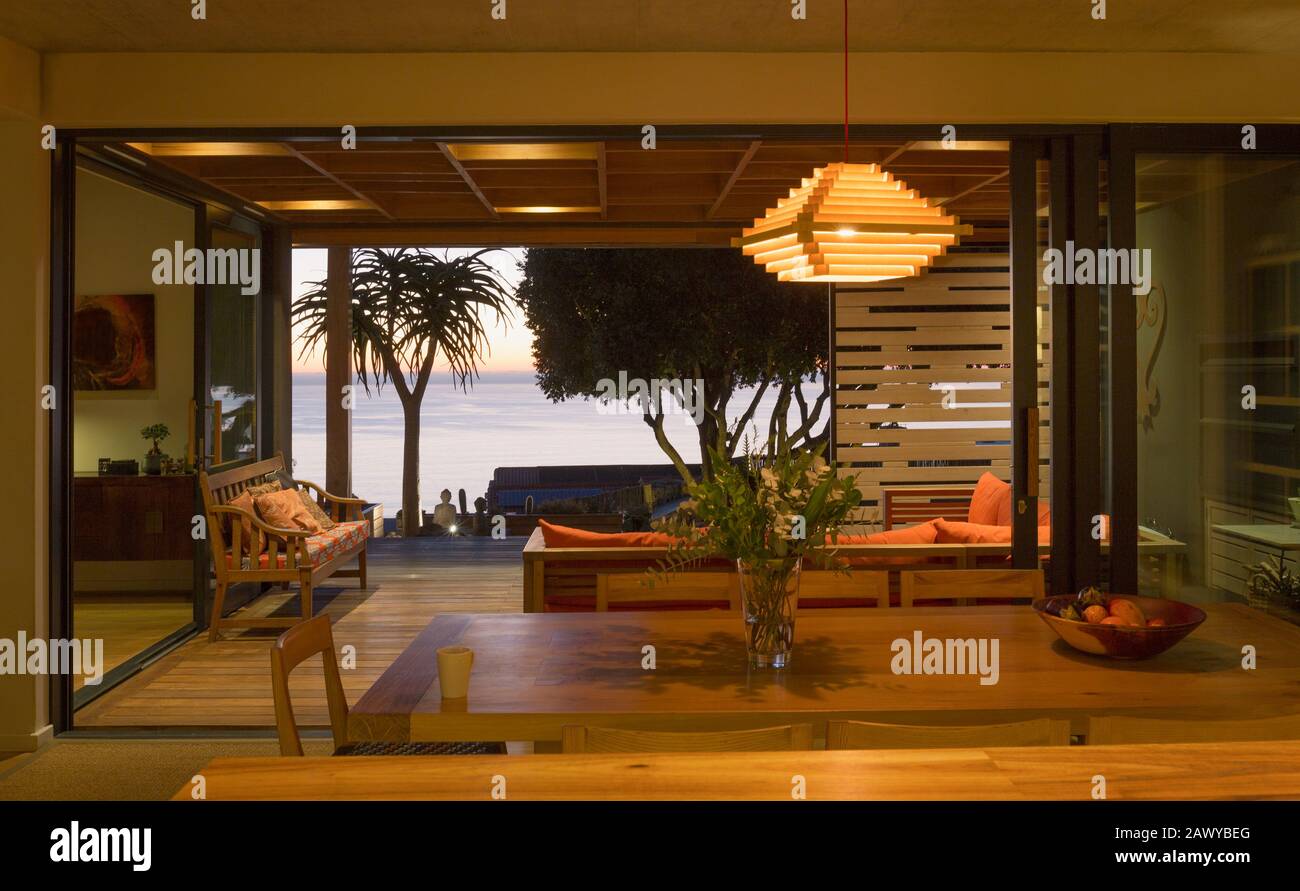 Sala da pranzo interna illuminata, moderna e lussuosa, aperta sul patio con vista oceano Foto Stock