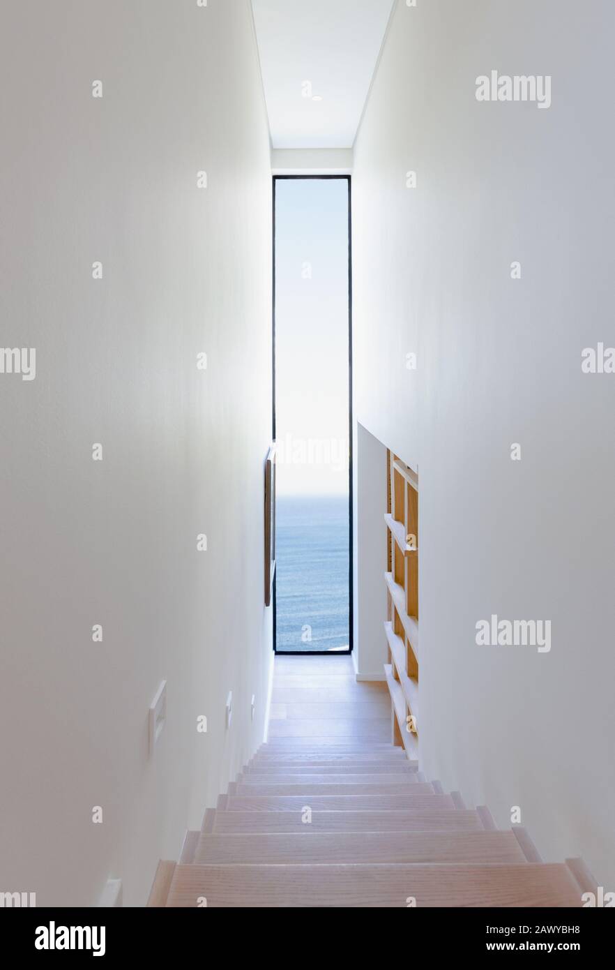 Le scale si affacciano su lunghe finestre con vista dell'oceano in interni moderni e lussuosi Foto Stock