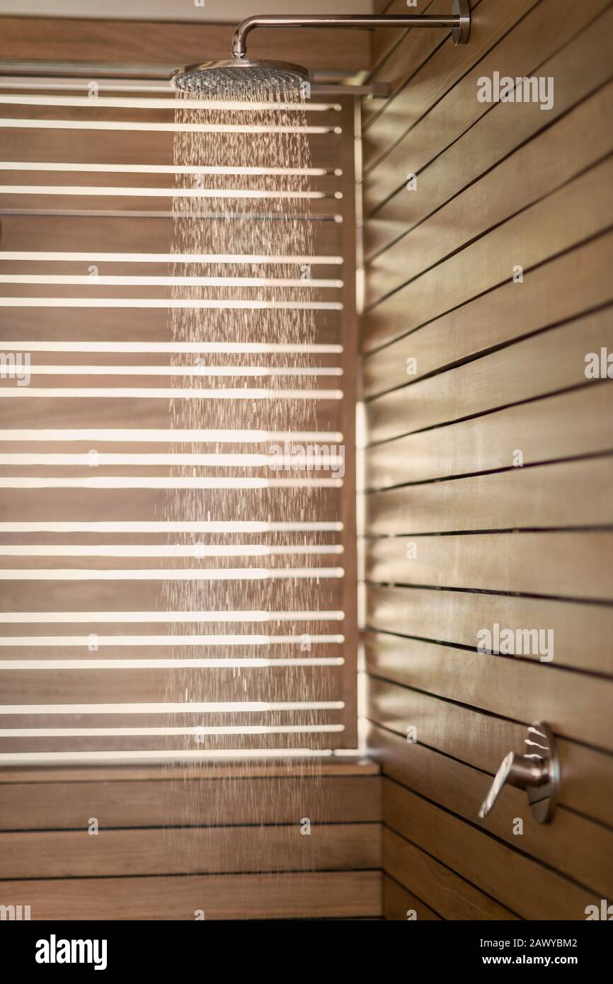 L'acqua cade dalla doccia a pioggia nella doccia in legno Foto Stock