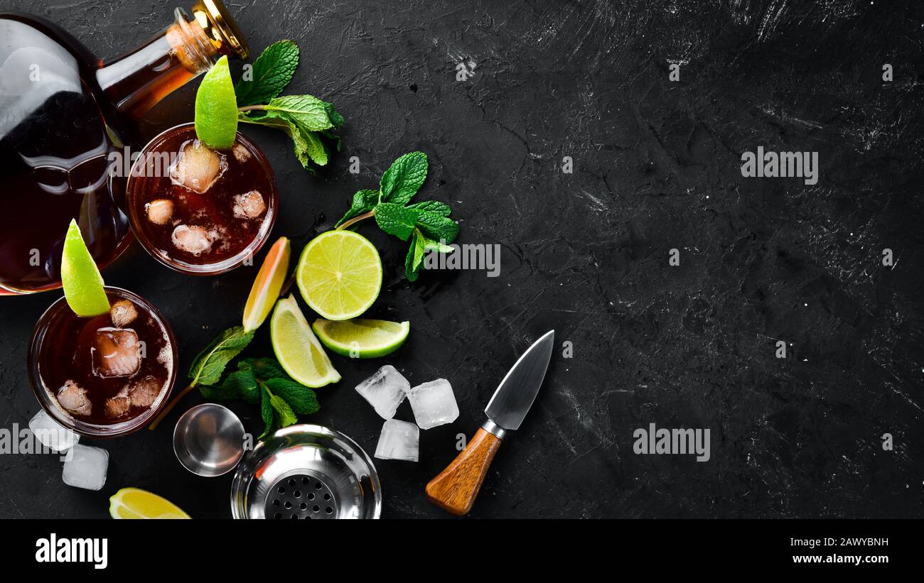 Bevande alcoliche Rum, lime e menta su sfondo di pietra nera. Vista dall'alto. Spazio libero per il testo. Foto Stock