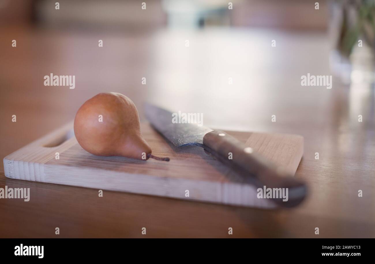Coltello ancora vita e pera su tagliere di legno Foto Stock