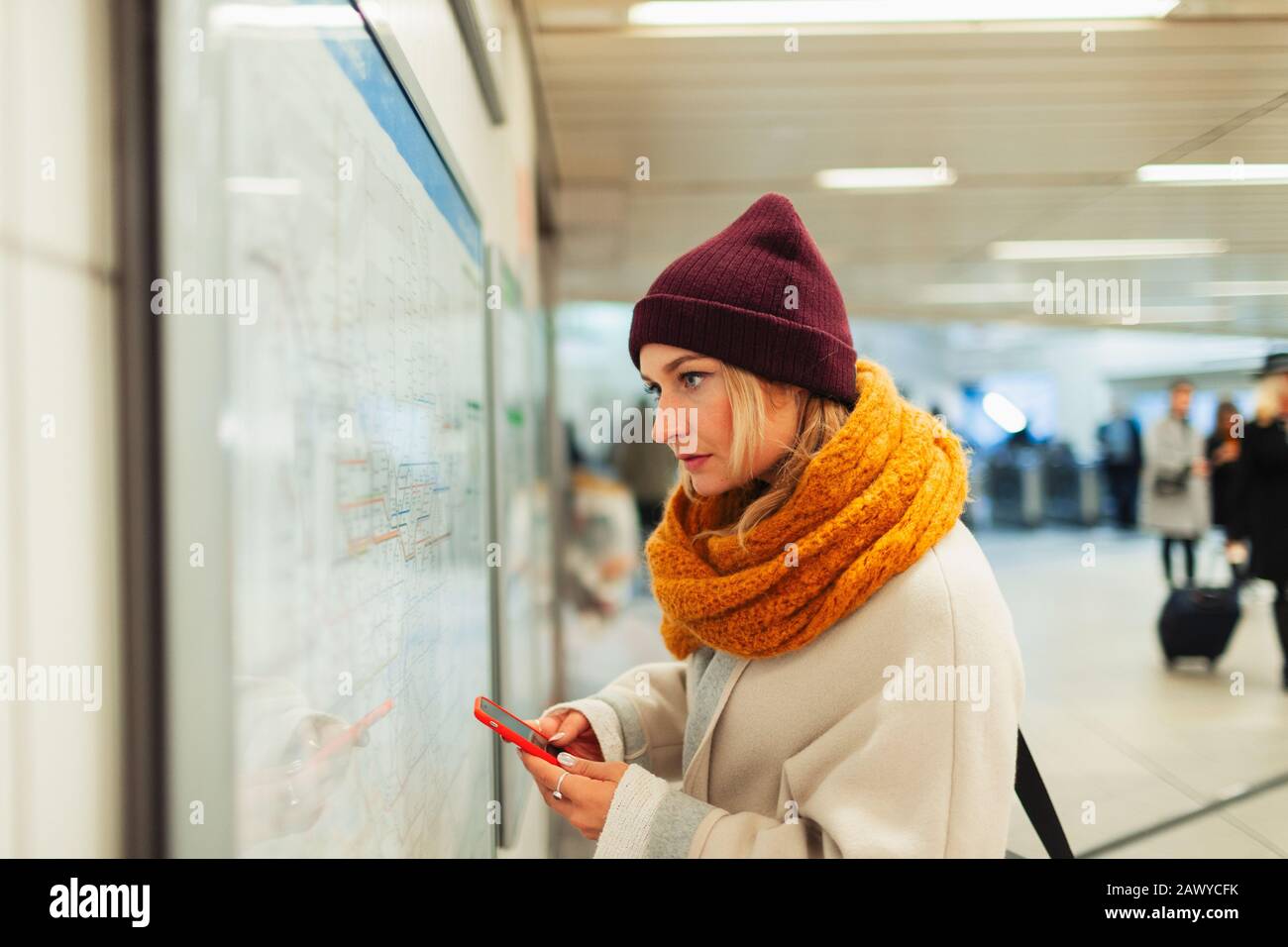 Giovane donna con smart phone che controlla la mappa della metropolitana Foto Stock