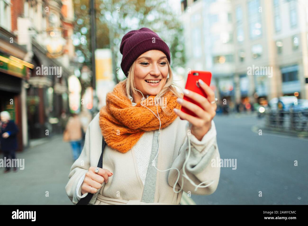 Giovane donna con cuffie e smart phone video chat su strada autunno Foto Stock