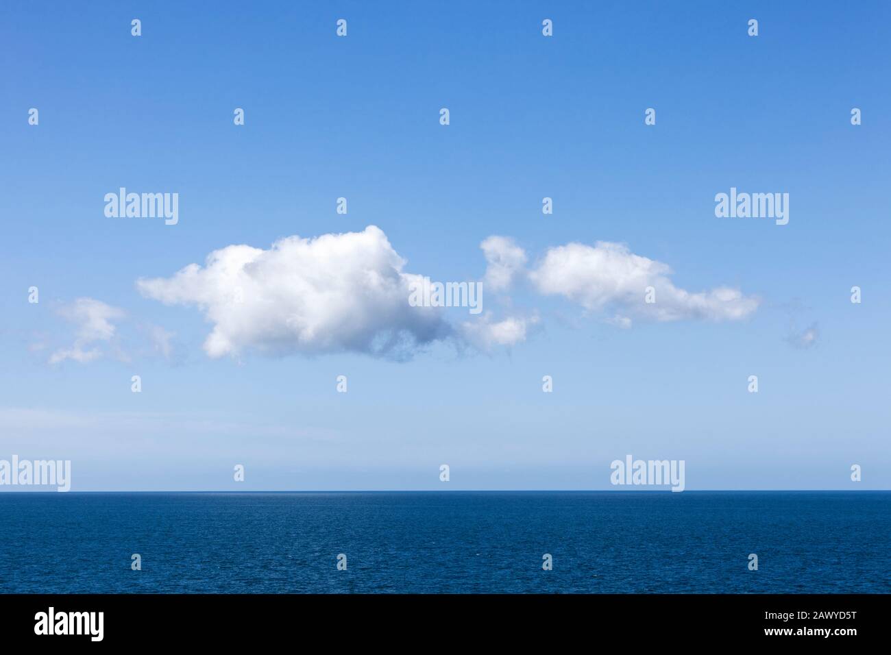 Le nuvole di Cumulus si formano in un cielo azzurro chiaro su un orizzonte calmo dell'oceano Foto Stock