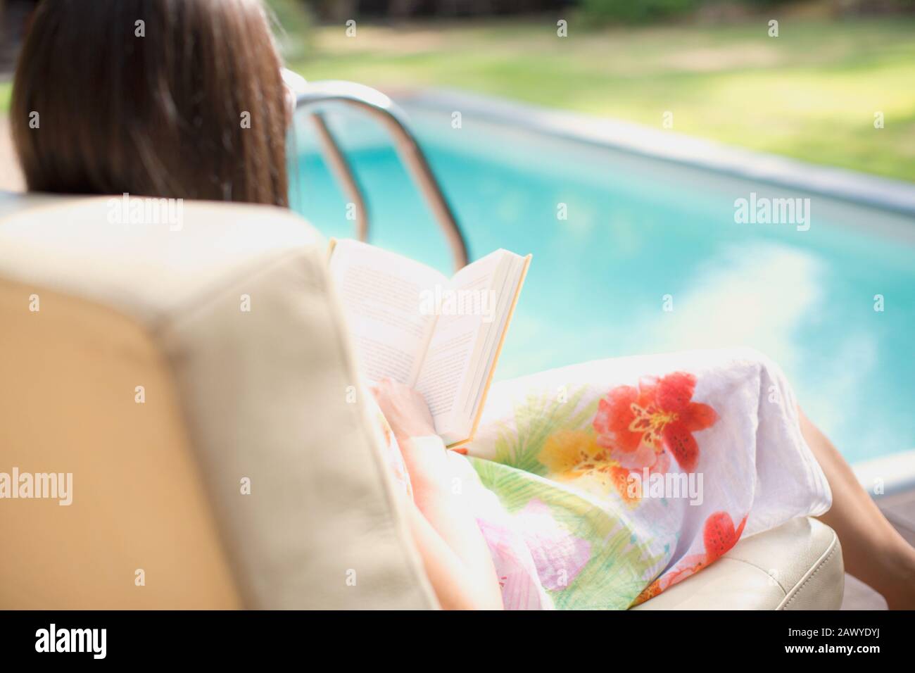 Donna rilassante, libro di lettura a bordo piscina estiva Foto Stock